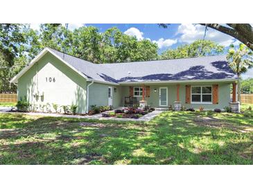 Charming single-story home featuring a landscaped front yard with flowers and an inviting front porch with rustic wood pillars at 106 Corbett Rd, Lithia, FL 33547