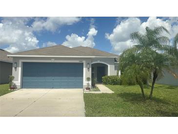 Well-maintained home with a blue garage door, palm trees, and a manicured lawn at 13443 Graham Yarden Dr, Riverview, FL 33579
