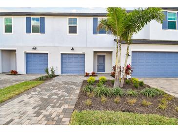 Charming townhome with blue garage doors, shutters, brick driveway and beautifully landscaped front yard at 5425 Tripoli Dr, Palmetto, FL 34221