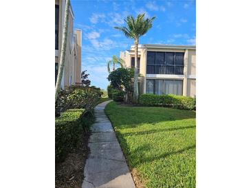 A beautiful condo exterior featuring lush landscaping and well-maintained grounds, with a sidewalk in view at 8744 54Th W Ave # 8744, Bradenton, FL 34210