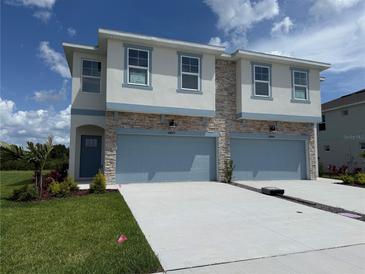 Beautiful two-story townhome with stone accents, light blue trim, and a two-car garage at 14012 Emerald Fields Dr, Hudson, FL 34667