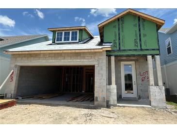 Unfinished house exterior showing open garage and front door entry under blue skies at 7963 Chandler Lake Ct, Hudson, FL 34667