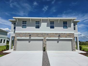Charming townhome featuring a stone facade, two-car garage, and a well-manicured lawn at 13904 Emerald Fields Dr, Hudson, FL 34667