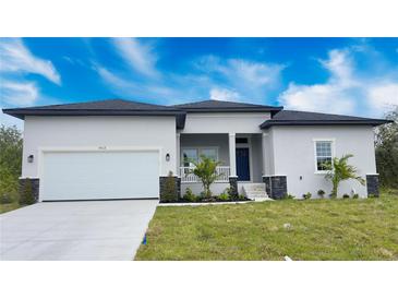 Charming single-story home with a two-car garage, landscaped front yard and covered front entry at 14112 Monserrate Ln, Port Charlotte, FL 33981