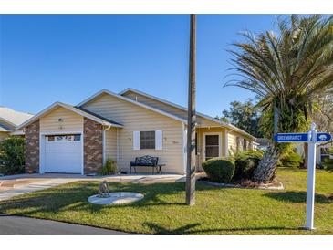 Cute yellow house with brick accents, attached garage, and a small front yard at 5846 Greenbriar Ct, Zephyrhills, FL 33542
