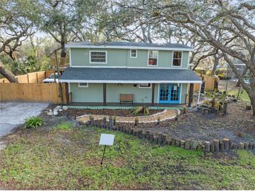 Charming two-story home with bright blue doors, a cozy front porch, and lovely yard landscaping at 10020 Jungle St, New Port Richey, FL 34654
