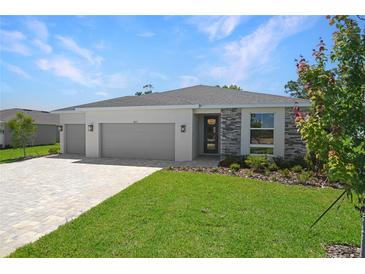 Well maintained lawn and landscaping highlight this single-story home with a two car garage and brick paver driveway at 9071 Players Dr, Weeki Wachee, FL 34613