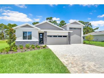 Beautiful, modern home with manicured lawn and paver driveway on a sunny day at 9093 Players Dr, Weeki Wachee, FL 34613