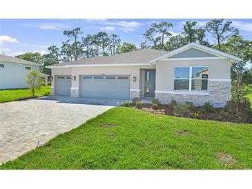 Charming single-Gathering home features a three-car garage, stone accents, and well-manicured lawn at 9109 Players Dr, Weeki Wachee, FL 34613