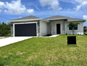 Charming single-story home showcasing a lush lawn, complemented by a sleek, dark garage door and stone accents at 183 Wright Drive, Rotonda West, FL 33947