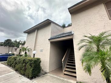 Condo exterior showcasing well maintained stucco walls, green shrubbery and stairs leading to the entrance at 7522 Needle Leaf Pl # 27, Tampa, FL 33617