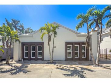 Charming property featuring a symmetrical facade with dark window frames and palm tree landscaping against a clear blue sky at 115 N Blvd Of The Presidents, Sarasota, FL 34236