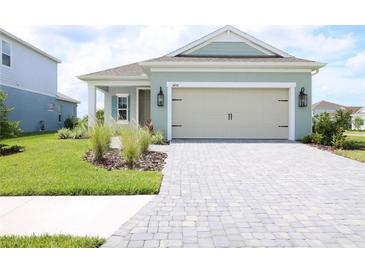 Charming single-Gathering home with a light green exterior, a two-car garage, and manicured landscaping at 14552 Skipping Stone Loop, Parrish, FL 34219