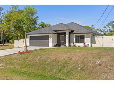 Beautiful single-story home showing the attached two-car garage, dark roof, lawn, and side fence at 2723 Jollivette Rd, North Port, FL 34288