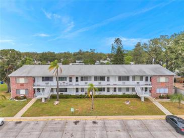 Two-story apartment complex featuring brick accents, palm trees, and exterior staircases under a bright blue sky at 2353 Shelley St # 10, Clearwater, FL 33765