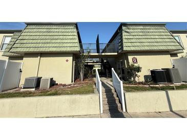 Building exterior showing stairs leading to second level, neutral paint and olive color metal roof at 1799 N Highland Ave # 143, Clearwater, FL 33755