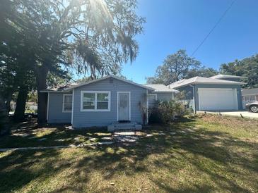 Charming single-story home with blue siding and a detached garage, surrounded by mature trees in a residential neighborhood at 8702 El Portal Dr, Tampa, FL 33604
