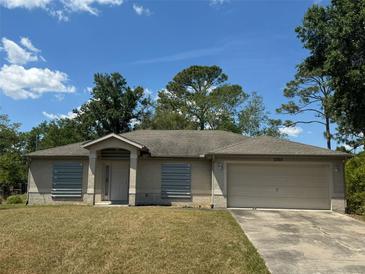 Inviting single-story home with a well-maintained lawn, a two-car garage, and storm shutters at 2305 De Vore St, North Port, FL 34291