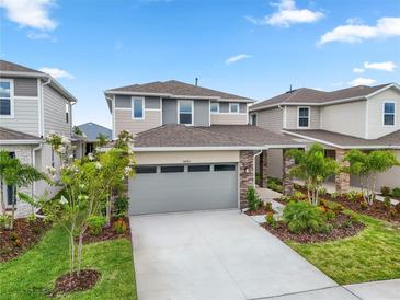 Charming two-story home features a two-car garage, well-manicured lawn, and lush landscaping at 6042 Jensen View Ave, Apollo Beach, FL 33572