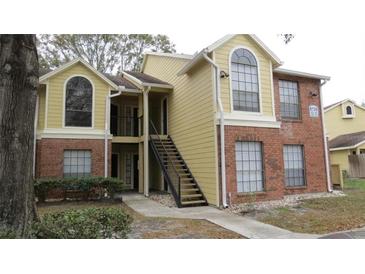 Two-story condo building featuring a brick and yellow exterior with a black stairway and large windows at 8728 Mallard Reserve Dr # 103, Tampa, FL 33614