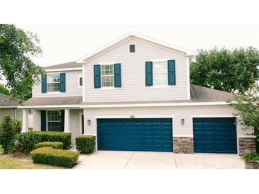 Charming two-story home featuring light gray siding, dark blue shutters, well-maintained landscaping, and a three car garage at 12236 Fairlawn Dr, Riverview, FL 33579
