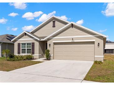 Charming single-Gathering home featuring neutral paint, a two-car garage, and a well-manicured front lawn on a sunny day at 16750 Sunburst Lake St, Wimauma, FL 33598