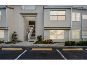 Beige condo building featuring reserved parking, stairs to upper units, and tidy landscaping at 6151 Bahia Del Mar Blvd # 125, St Petersburg, FL 33715