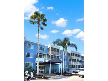 Beautiful exterior view of a blue condominium complex with palm trees and a covered entrance at 2700 Coconut Bay Ln # 419, Sarasota, FL 34237