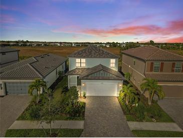 Charming two-story home with landscaped yard and paver driveway set against a colorful sunset backdrop at 6288 Winding Pine Dr, Nokomis, FL 34275