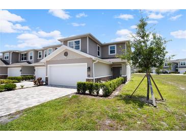 Charming two-story townhome featuring an attached two-car garage and beautifully maintained front yard landscaping at 5367 Riverwalk Preserve Dr, New Port Richey, FL 34653