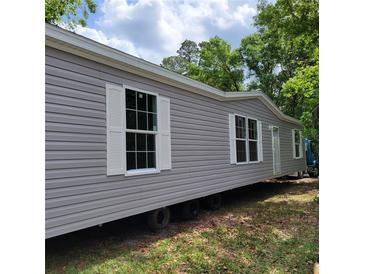 Gray manufactured home with white shutters and a spacious yard at 2459 Ayerswood Dr, Brooksville, FL 34604