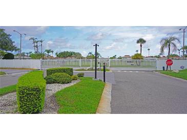 Gated community entrance with white fencing, manicured landscaping, and a clearly marked stop sign at 4329 Tahitian Gardens Cir # B, Holiday, FL 34691