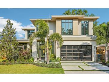 Stunning modern home featuring a sleek design, large windows, and a glass garage door at 1630 Douglas Ave, Dunedin, FL 34698