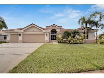 Beautiful one-story home with three-car garage, lush landscaping, and palm trees at 10301 Manta Way, Tampa, FL 33615