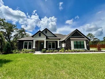 Charming single-story home featuring stone accents, a covered porch, and a lush green lawn at 17059 Nokota Ave, Hudson, FL 34667