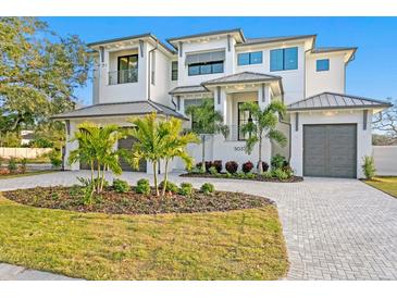Stunning two-story home featuring lush landscaping, a circular driveway, and a three-car garage at 5032 W Longfellow Ave, Tampa, FL 33629