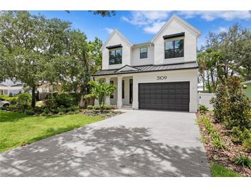 Stunning two-story home featuring a modern design, lush landscaping, and a gray brick driveway at 3109 W Knights Ave, Tampa, FL 33611