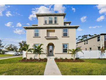 Two-story house with light beige siding, palm trees, and a white fence at 1323 W Arch St, Tampa, FL 33607