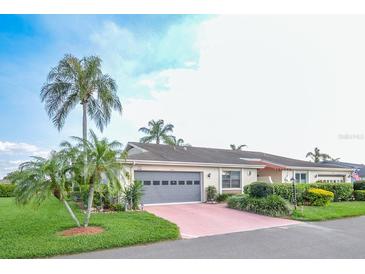 Single-story home with attached garage and well-manicured landscaping at 2410 Lancaster Dr, Sun City Center, FL 33573