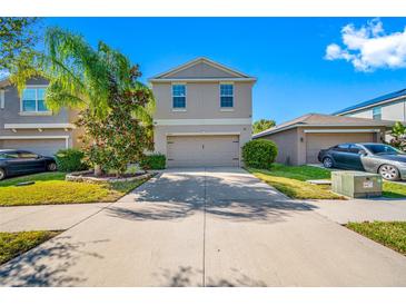 Charming two-story home featuring a neutral color scheme, well-manicured lawn, and a spacious two-car garage at 17035 Peaceful Valley Dr, Wimauma, FL 33598