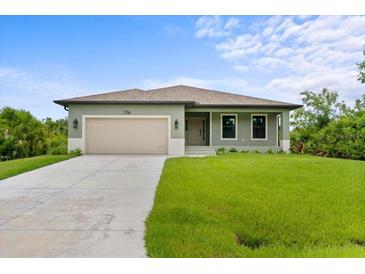 Newly constructed home with a light green exterior, a two-car garage, and a well-manicured lawn at 156 Haddock Dr, Rotonda West, FL 33947