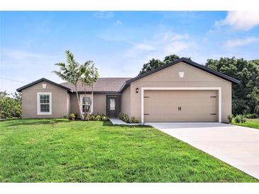 Tan one-story house with a two-car garage and lush lawn at 12461 Patsy Ave, Port Charlotte, FL 33981