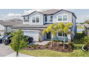 Two-story house with a three-car garage and landscaped front yard at 12964 Willow Grove Dr, Riverview, FL 33579