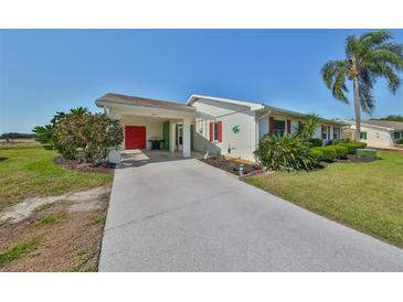 Charming single-story home featuring well-manicured landscaping, vibrant red accents, and a convenient covered carport at 218 Glenellen Pl, Sun City Center, FL 33573