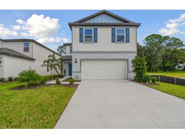 Two-story house with light beige siding, blue shutters, and a two-car garage at 10624 Hidden Banks Gln, Parrish, FL 34219