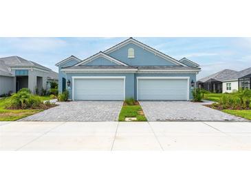 Two-car garage home with light blue exterior and landscaping at 12706 Palatka Dr, Venice, FL 34293