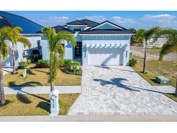 Charming, light-blue single-Gathering home featuring a well-manicured lawn, paver driveway, and a two-car garage at 6542 Simone Shores Cir, Apollo Beach, FL 33572