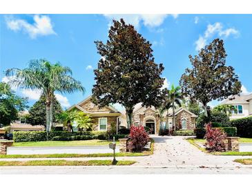 Charming home showcasing lush landscaping, palm trees, and a brick paved driveway at 1227 Toscano Dr, Trinity, FL 34655