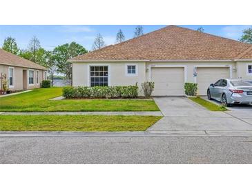 Front view of a house with a garage and landscaped yard at 5723 Autumn Shire Dr, Zephyrhills, FL 33541