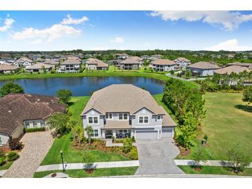 Beautiful two-story home boasts a serene lake view, lush landscaping and paver driveway at 7135 Graybrook Dr, Wesley Chapel, FL 33545